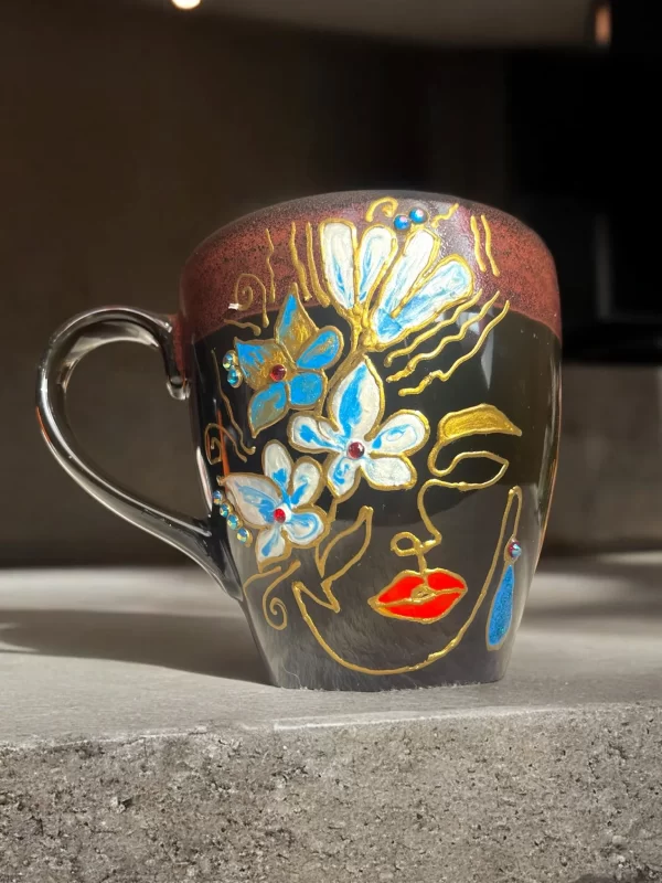 Handcrafted Black Ceramic Face Mug with Blue Floral and Gold Accents - Image 2